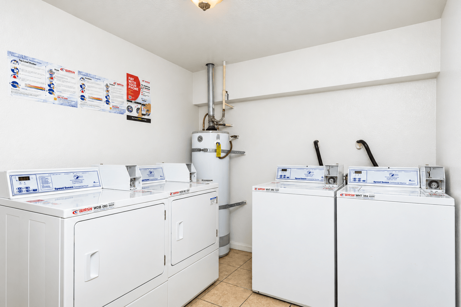 A row of washing machines are lined up in a small room.